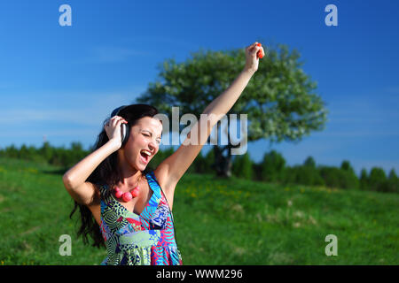 Giovane donna con le cuffie per ascoltare musica sul campo Foto Stock