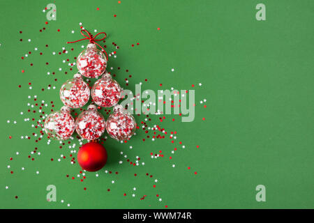 Vetro palle di Natale con Stella glitter all'interno disposti in forma di un albero di Natale su sfondo verde. Lay piatto Foto Stock