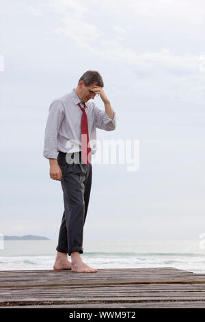 Premuto o preoccupati imprenditore a piedi nudi al mare Foto Stock