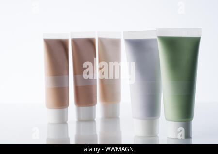 Molti tubi cosmetici con creme piedi su sfondo riflettente Foto Stock
