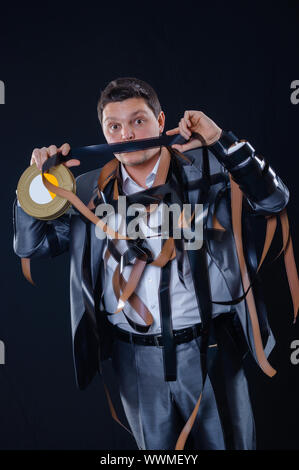 Un giovane uomo in un vestito con il cine-film su uno sfondo nero in studio Foto Stock