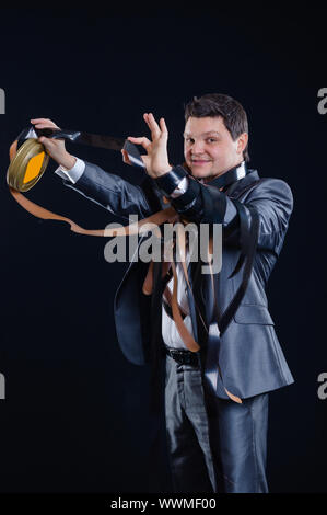 Un giovane uomo in un vestito con il cine-film su uno sfondo nero in studio Foto Stock