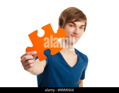 Giovane uomo in possesso di un pezzo di puzzle isolati su sfondo bianco, concetto soluton Foto Stock