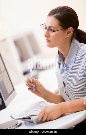 La donna nella sala computer volteggiare gli elementi in un giornale Foto Stock