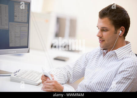 Uomo in sala computer ascoltando mp3 player Foto Stock