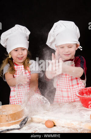 Due giochi per bambini con la farina su sfondo scuro Foto Stock