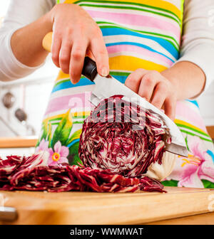 Donna con le mani in mano il taglio di cavolo rosso, dietro di verdure fresche. Foto Stock