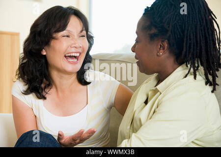 Conversazione tra due donne in salotto e sorridente Foto Stock