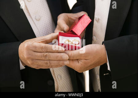 Lo sposo e padre tenendo gli anelli di nozze Foto Stock