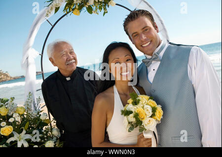 Sposa e lo sposo con sacerdote sotto Archway Foto Stock
