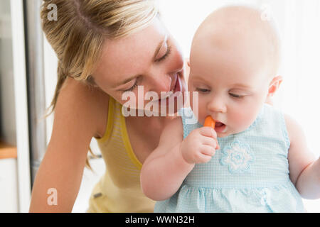 La madre e il bambino in cucina a mangiare la carota Foto Stock