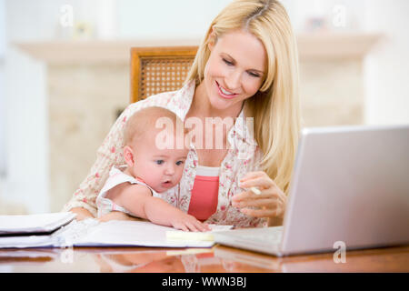 La madre e il bambino nella sala da pranzo con laptop sorridente Foto Stock