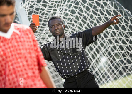 Arbitro di calcio tenendo fuori un cartellino rosso Foto Stock