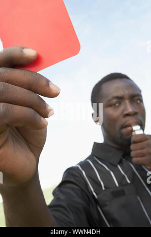 Arbitro di calcio tenendo fuori un cartellino rosso Foto Stock