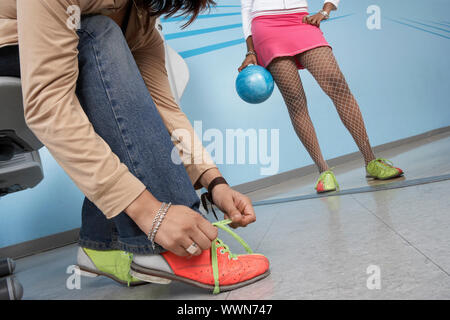 Giovane donna di legatura scarpe da bowling Foto Stock