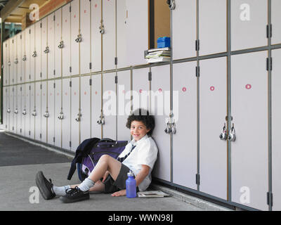 Scuola ragazzo in attesa nei pressi di armadietti Foto Stock