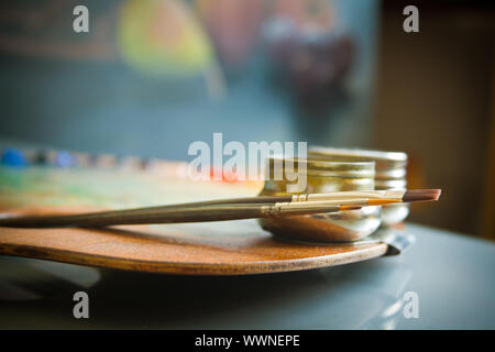 Pittore di legno della tavolozza con tre artisti dei pennelli e acciaio twin campionatori a immersione close-up su sfondo di still-life pittura in art studio interno. Foto Stock