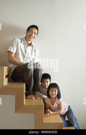 Uomo seduto con i bambini sulle scale Foto Stock