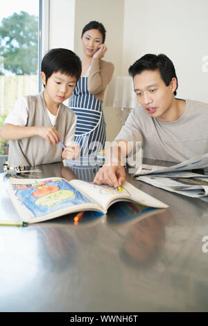 Giovane uomo aiutando figlio con libro da colorare Foto Stock