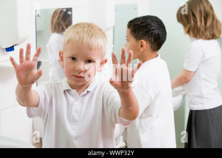 Gli studenti in bagno lavelli a lavarsi le mani con una sola azienda in alto le mani e sapone (messa a fuoco selettiva) Foto Stock