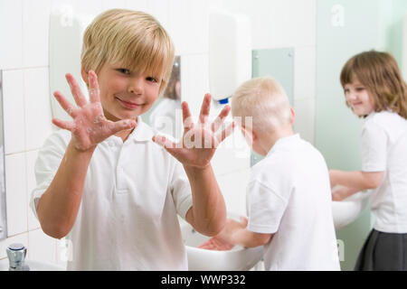 Gli studenti in bagno lavelli a lavarsi le mani con una sola azienda in alto le mani e sapone (messa a fuoco selettiva) Foto Stock