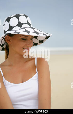 Bruna sorgeva su una spiaggia indossando polka dot hat Foto Stock