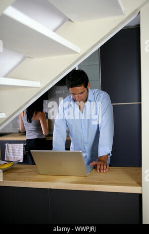 Matura in cucina con il computer portatile Foto Stock