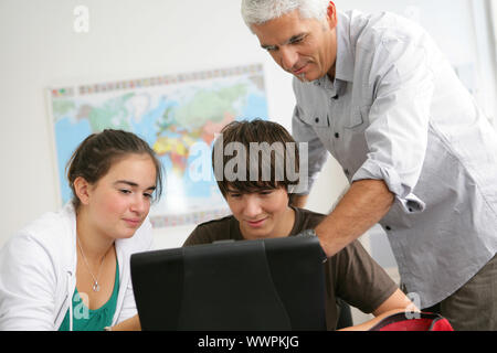 Gli studenti con un insegnante dietro un computer portatile Foto Stock