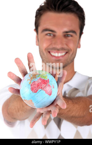 Uomo sorridente holding globe Foto Stock