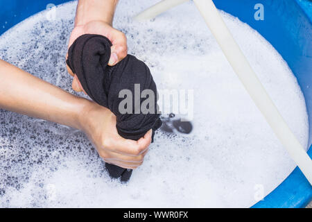 Mani femminili lavare gli indumenti a mano con detersivo in vasca. messa a fuoco selettiva e spazio per il testo. Foto Stock