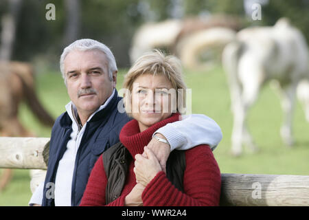 Matura in piedi nella parte anteriore del campo di cavalli Foto Stock