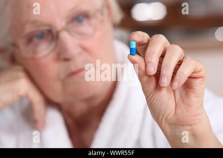 Una vecchia donna di prendere una pillola. Foto Stock