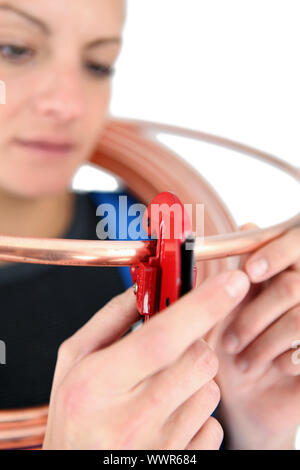 Donna aggancio di una chiave a tubo su un anello di rame Foto Stock