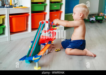 Carino baby boy giocare con modellini di auto sulla via nella stanza dei ragazzi Foto Stock