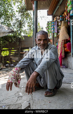 Kashmir un uomo seduto accanto a un negozio a Srinagar Foto Stock