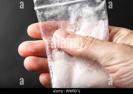 Polvere bianca di farmaco in un piccolo sacchetto di plastica in mano. luogo per il testo Foto Stock