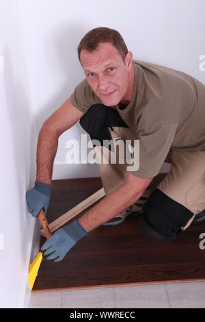 Un uomo la posa di parquet. Foto Stock