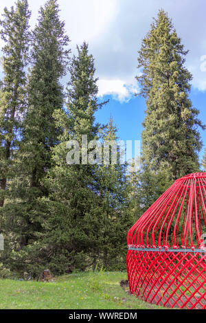 Quasi ready-made tradizionale del Kirghizistan yurt casa sullo sfondo di montagne coperte di bosco di conifere. Kirghizistan Foto Stock