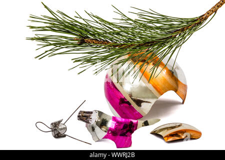 Rotture di palla di Natale si trova al disotto del ramo del pino, isolato su sfondo bianco Foto Stock