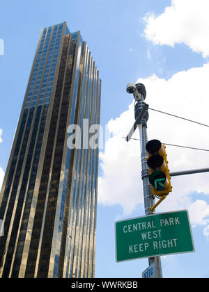 Central Park West cantare appeso a un semaforo a fianco di un grattacielo in un nuvoloso cielo blu sullo sfondo. Foto Stock