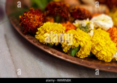 Primo piano il lato orizzontale angolazione di fiori di tagete su un thali o piastra per puja preparati. Immagine di sfondo di indù rituali tradizionali con Foto Stock