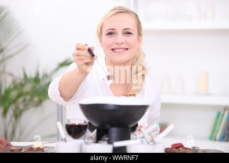 Donna avente una Fondue bourguignonne Foto Stock