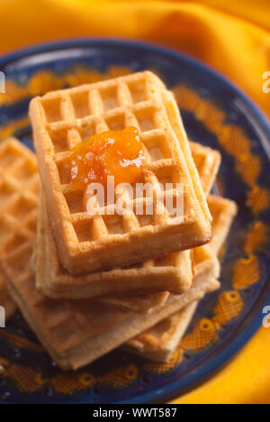 Confettura di albicocca sul belga cialde impilate su una piastra di blu e arancione igienico Foto Stock