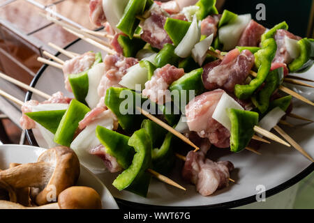 Il pepe verde e spiedini di carne di maiale nel recipiente Foto Stock