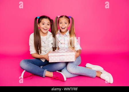 Close up foto due piccoli età ha le sue ragazze tenendo entrambi i bracci di mani un grande giftbox migliori amici sit piano casual wear jeans denim plaid a scacchi Foto Stock