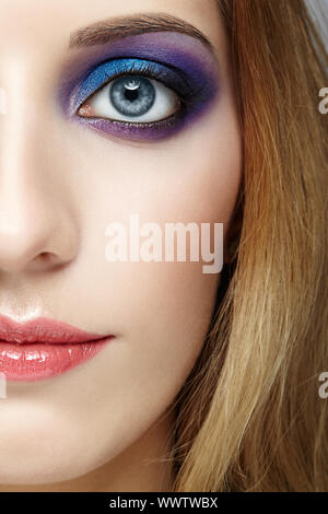 Metà femmina faccia con e viola e blu occhi trucco Foto Stock