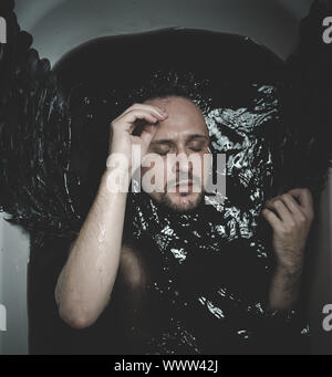 Il gotico, Angelo caduto, uomo in una vasca con acqua nera e le ali, sommerse, depressione, perdita Foto Stock