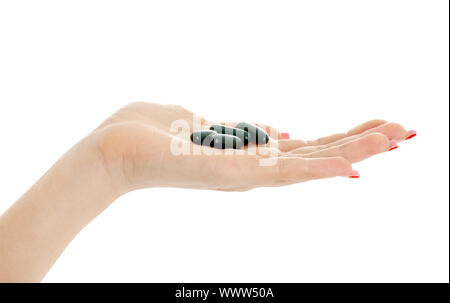 Primo piano di Palm con le pillole di verde su bianco Foto Stock