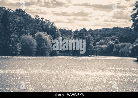 Vecchia foto d'epoca. River sun glare shore foresta di alberi di nuvole del cielo lo spazio di copia Foto Stock