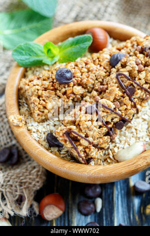 Barrette di cereali con noci e cioccolato in una ciotola con fiocchi di avena. Foto Stock